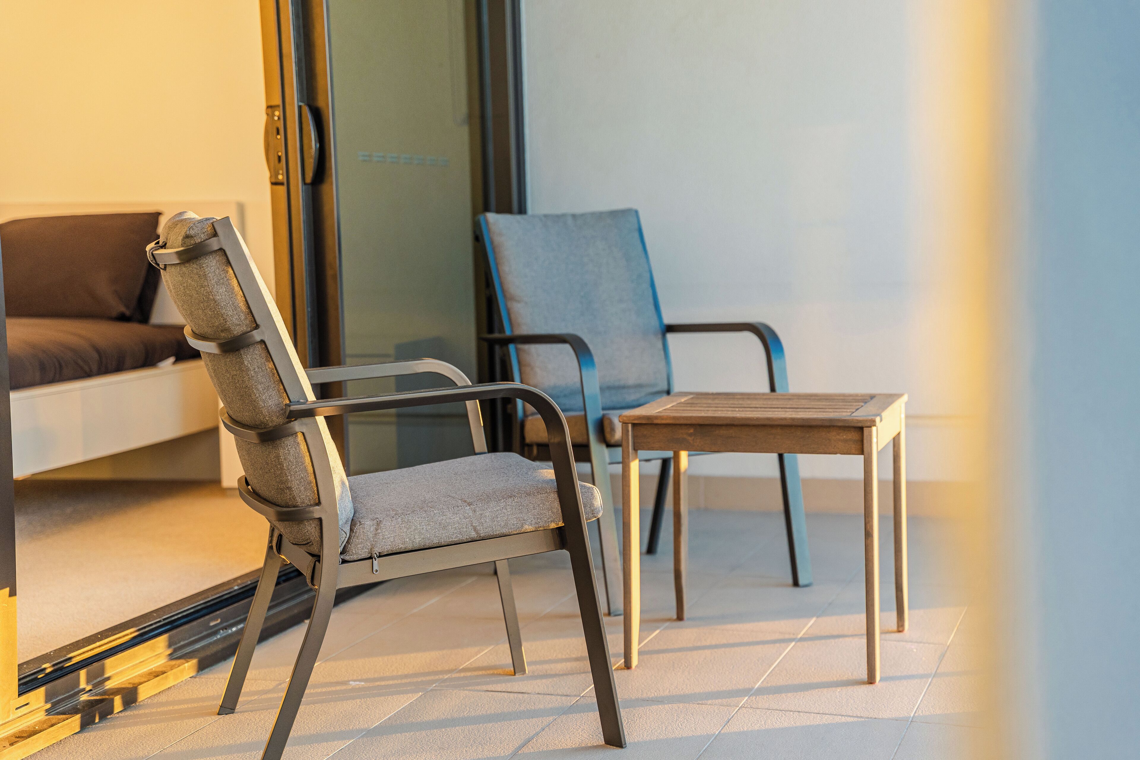 A modern outdoor seating area with a sofa, two chairs, and a small table.