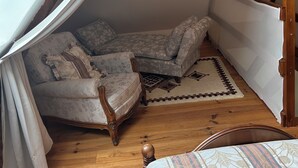 A bedroom with a canopy bed, two upholstered chairs, a wooden floor, and a patterned rug. - Gîte near Honfleur (Gonneville-sur-Honfleur)