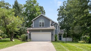 A two-story house with a garage, surrounded by trees and a well-maintained lawn.