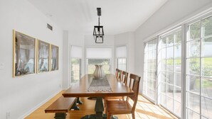 A dining room with a long wooden table, six chairs, and a chandelier.
