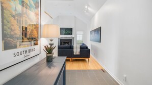A modern living room with a fireplace, a sofa, and a TV mounted on the wall.