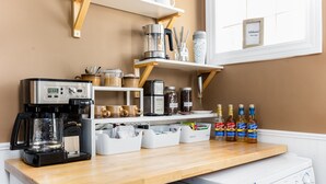 A kitchen with a coffee maker, jars, and bottles on the counter.