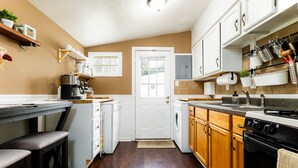 A kitchen with wooden cabinets, a stove, a sink, and a coffee maker.