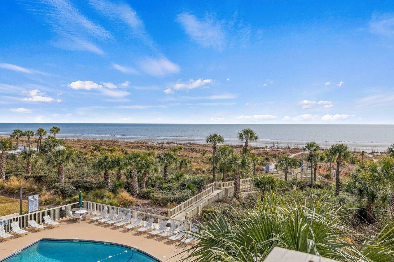 A pool area with a view of the beach and ocean.