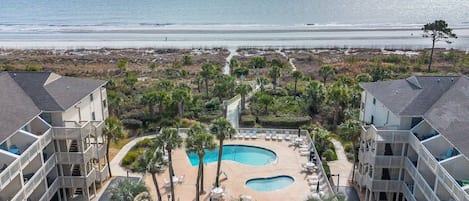 A resort with a pool area, multiple balconies, and a view of the ocean.