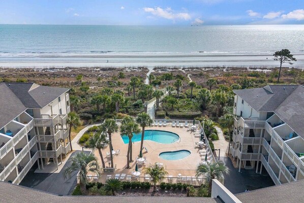 A resort with a pool area, multiple balconies, and a view of the ocean.