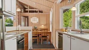 Eine moderne Küche mit Holzelementen, einem Essbereich und Blick auf Grünflächen.