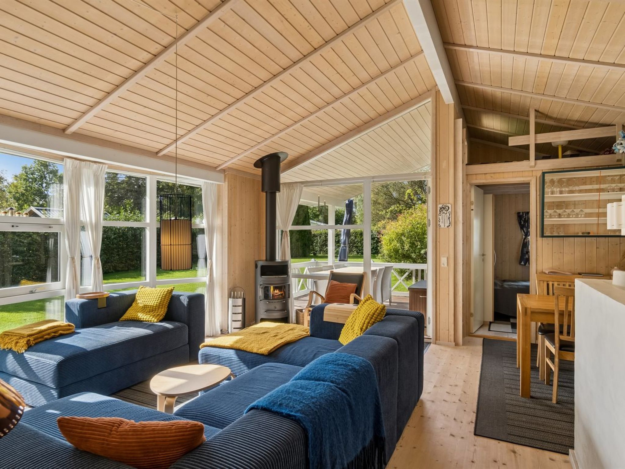 A covered outdoor living area with a sofa set, a table, and a wood-burning stove.