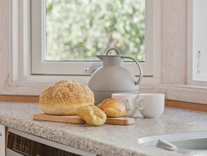 Un comptoir de cuisine avec une miche de pain, un croissant et une théière.
