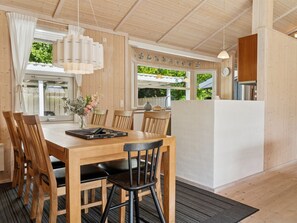 Un comedor de madera con una mesa, sillas y una encimera de cocina.