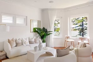 Uma sala de estar moderna com um sofá branco, uma mesa de centro e uma planta grande.