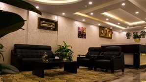 Eine moderne Lobby mit einer Couch, Sesseln, einem Empfangsschalter und dekorativer Wandgestaltung.