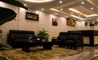 A modern lobby with a sofa and armchairs, a reception desk, and decorative wall art.