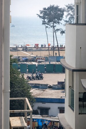 A view of a beach with people, a ship in the distance, and a row of green containers.