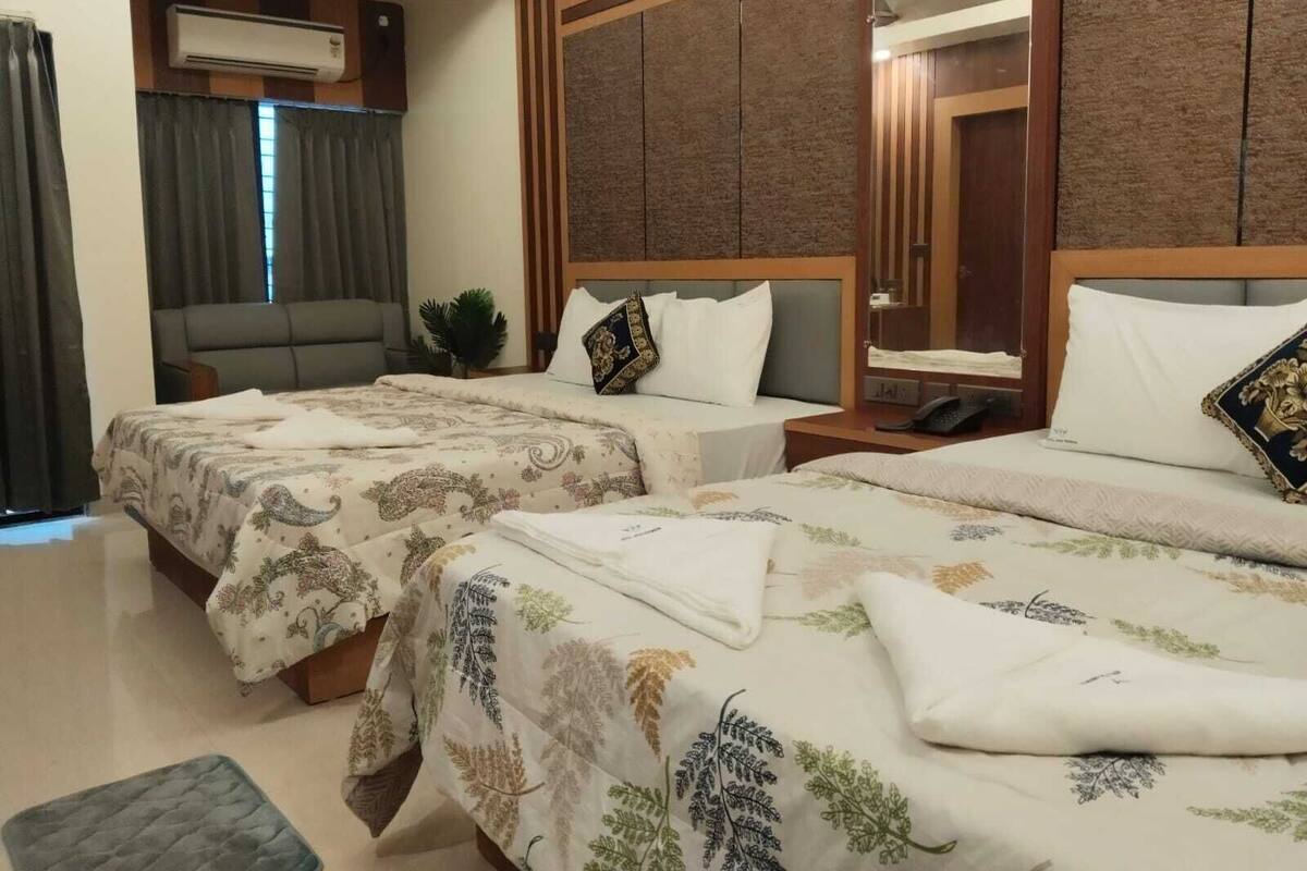 Une chambre d’hôtel avec deux lits, un canapé, une petite table et un miroir.
