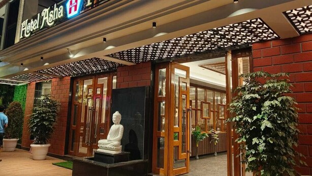 A hotel entrance with a Buddha statue, potted plants, and a sign reading "Hotel Asha Premium". - ASHA PREMIUM (Kanthi)