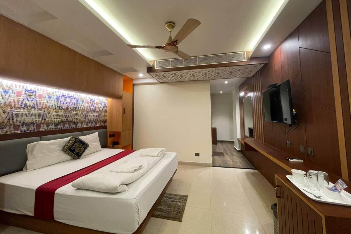 Une chambre d’hôtel moderne dotée d’un grand lit, d’une télévision à écran plat, d’un bureau avec un plateau de petit-déjeuner et d’un ventilateur de plafond.