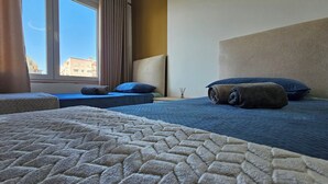 Una habitación de hotel con dos camas, una ventana con cortinas y vistas a edificios.