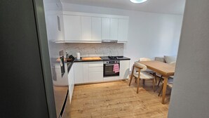 Una cucina funzionale con mobili bianchi, un piano di lavoro nero e un tavolo da pranzo in legno con sedie.