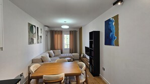 Un espacio habitable pequeño con comedor, sofá, estantería y un cuadro en la pared.