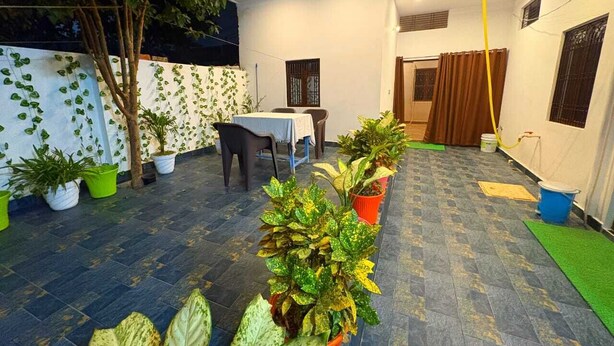 Un espace intérieur doté d’un sol carrelé, de plantes en pot, d’une table avec des chaises et d’un rideau.