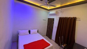 Une chambre d’hôtel équipée d’un lit, d’un ventilateur de plafond, d’un climatiseur, d’une porte et d’un rideau.
