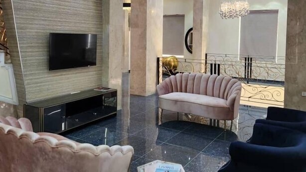 Una sala de estar moderna con un televisor de pantalla plana, un sofá rosa, un sillón negro y una mesita de centro.
