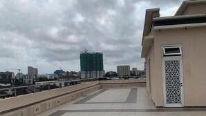 Terraza en la azotea con vistas a un paisaje urbano, incluyendo un edificio verde en construcción.