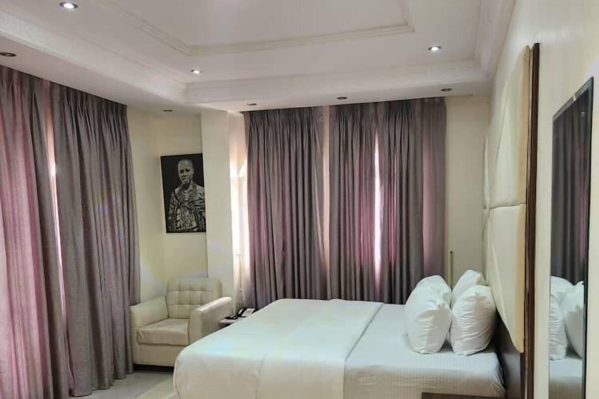 A modern bedroom with a large bed, a sofa, and a large mirror.