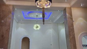 Zona de recepción con un escritorio de madera, un candelabro y un diseño de techo circular con iluminación empotrada.