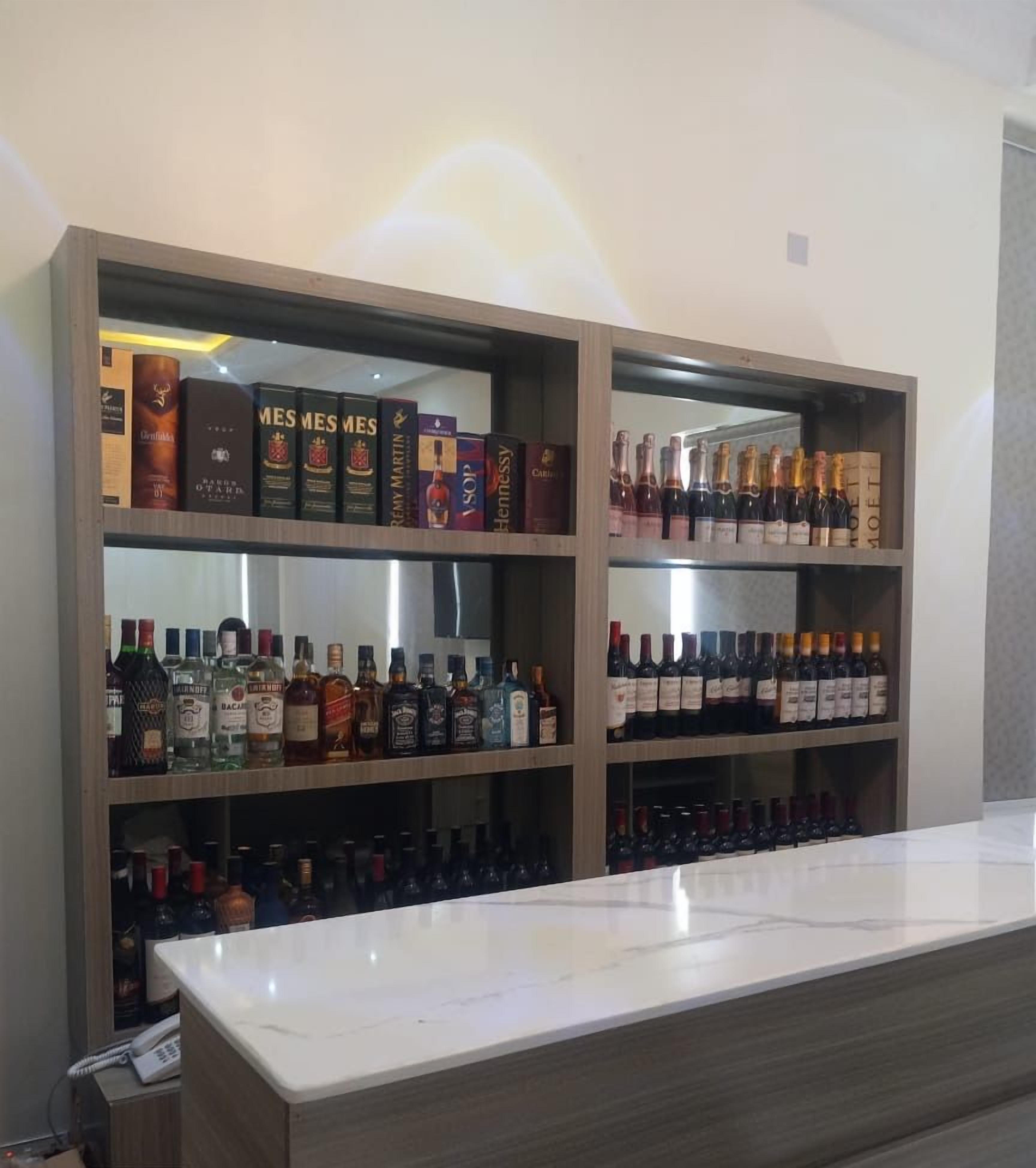 A bar area with shelves stocked with liquor bottles and boxes of whisky.