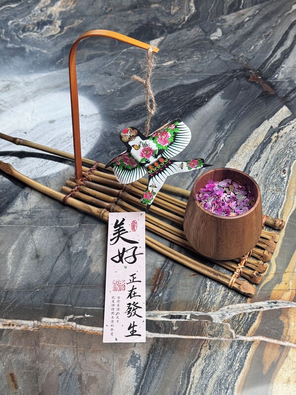 A decorative bird on a bamboo stand, a wooden bowl with dried flowers, and a sign with Chinese characters. - chongqingyinshiguangjiangjingjiudian (Chongqing)