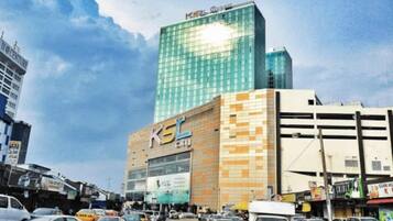 Un edificio de varios pisos con un llamativo letrero 'KSL', rodeado de automóviles estacionados y otros edificios.