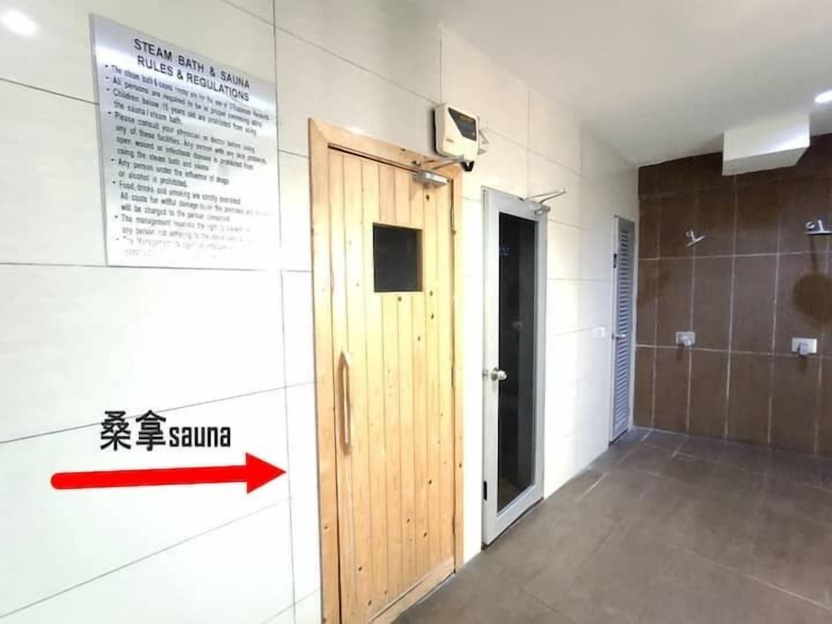Une porte en bois, au-dessus de laquelle est affichée une pancarte indiquant les « règles et consignes de sécurité du bain de vapeur et du sauna ».