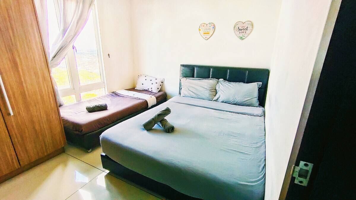 A bedroom with two beds, a wooden wardrobe, and a window with curtains.