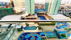 A high-rise building with a rooftop pool area, including a children's play zone and a large central pool.