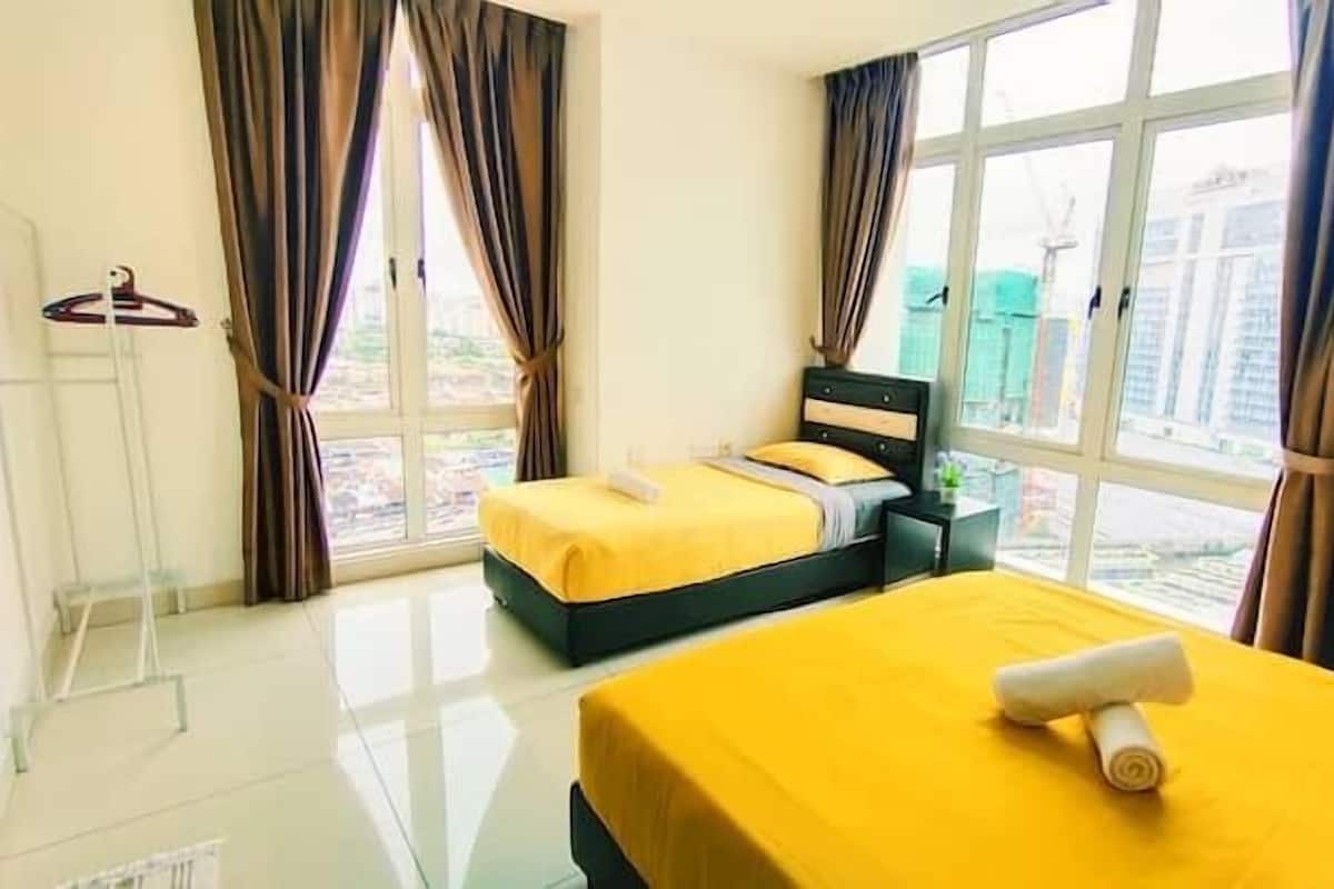 A hotel room with two beds, large windows, and curtains.
