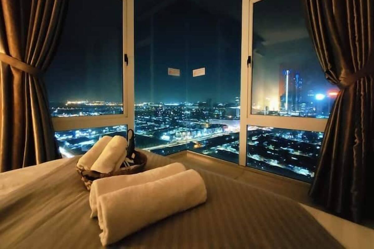 A hotel room with a large window offering a nighttime city view.