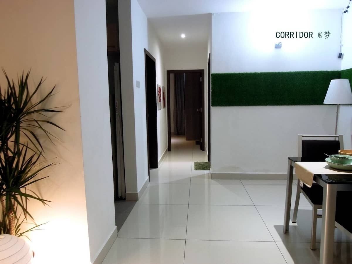 A hallway with a dining area, a potted plant, and a green wall.
