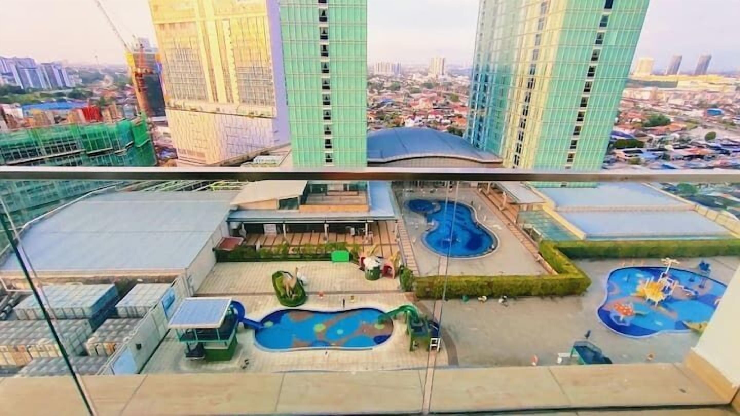 A high-rise building with multiple floors, a rooftop pool area with various water features, and a view of the surrounding cityscape.