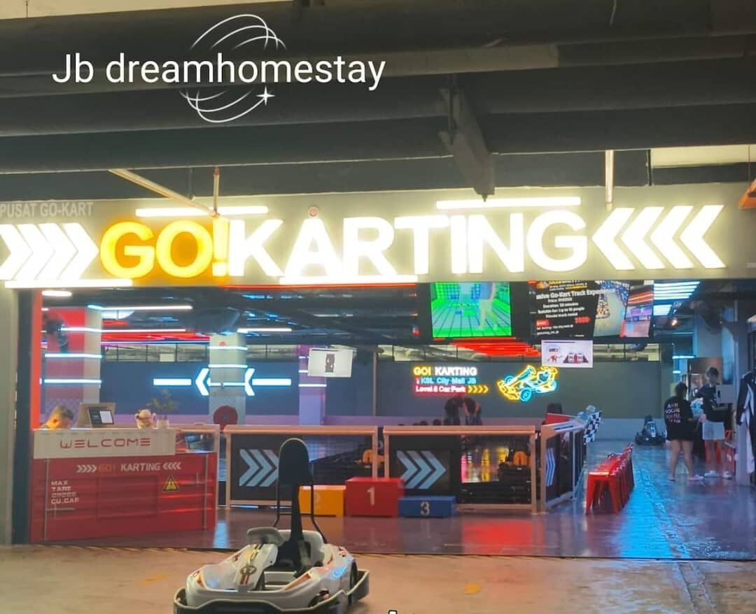 A go-karting area with a neon sign, a welcome desk, and numbered racing lanes.