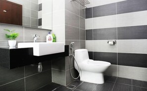 A modern bathroom with a white sink, a toilet, and a shower.