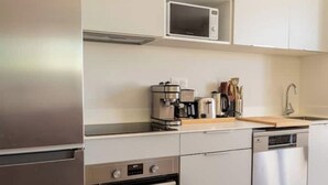 Una cocina moderna con electrodomésticos de acero inoxidable, microondas, cafetera y lavavajillas.