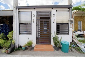Un bâtiment à la façade blanche, doté d’une grille en métal et agrémenté de plantes en pot.