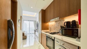 A modern kitchen with wooden cabinets, a built-in microwave, stove, and washing machine.
