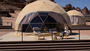 A dome-shaped tent with a clear window, a cushioned chair, and a small table.