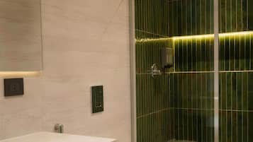 A modern bathroom with a glass shower enclosure, a white sink, and a toilet.