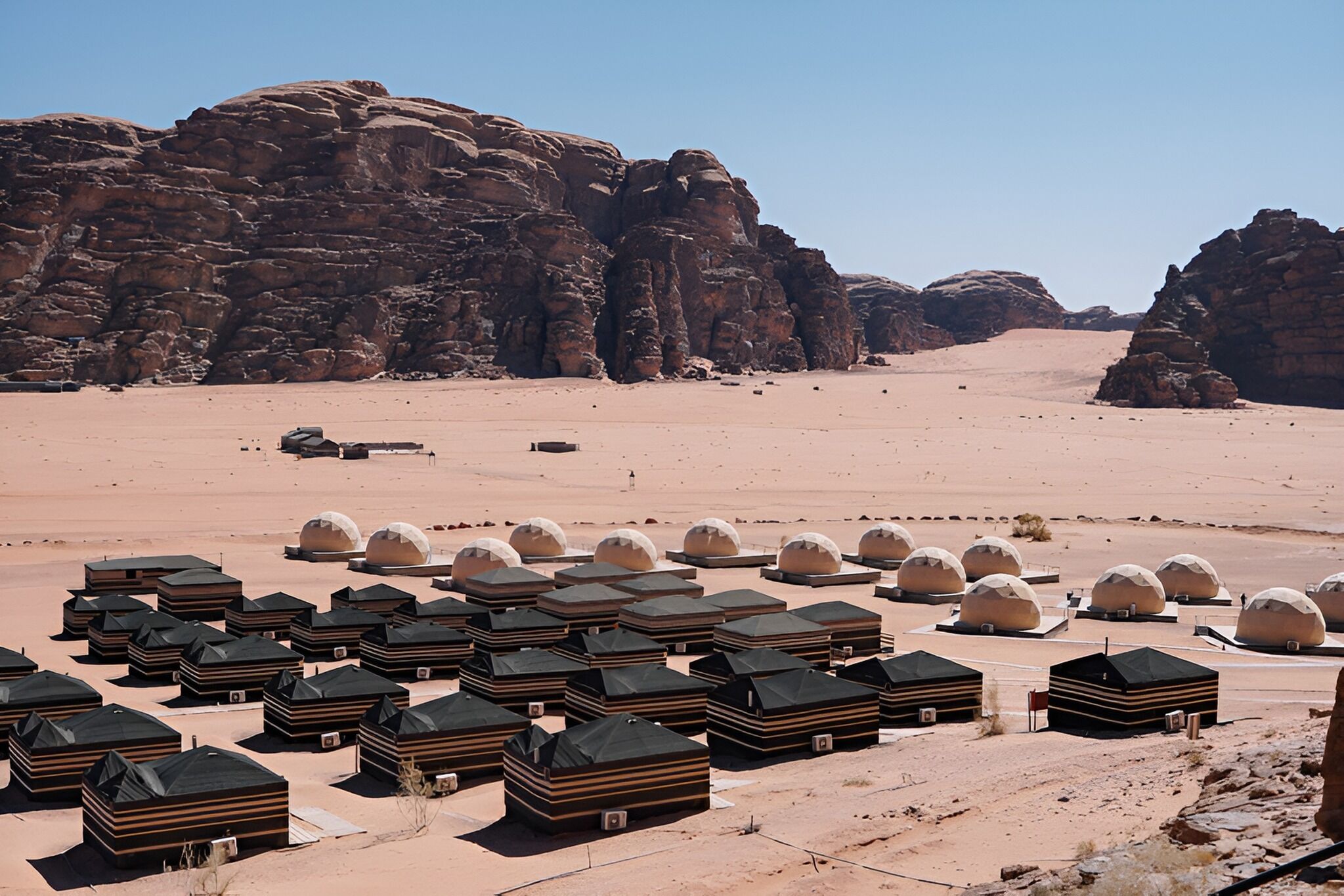 A desert landscape with multiple dome-shaped structures, likely accommodations, arranged in rows.