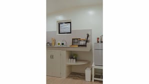 A kitchen with a microwave, toaster, and a small refrigerator. There is a sink with a faucet and a cabinet below it. - Caalan Cottage (El Nido)