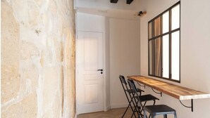 Une pièce avec une table en bois et quatre chaises, une grande fenêtre et une porte blanche.